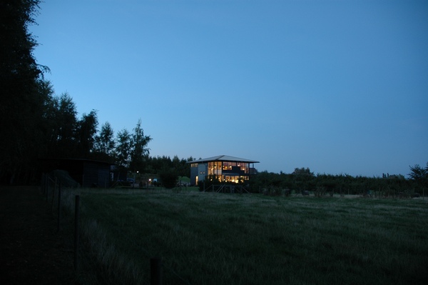 Huset i aftenlys med markerne foran